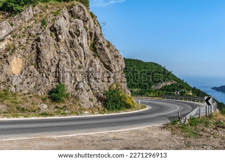 Highway in the mountains against the backdrop of the Adriatic Sea near Budva, Montenegro. Serpentine road among the rocks on the background of the sea landscape