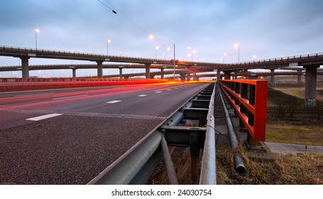 A Highway Overpass With Busy Traffic At Night. Various Roads Intertwining With Each Other