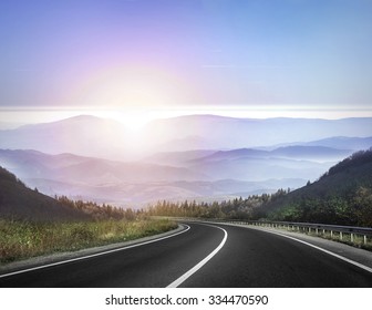 Highway road against mountains and a sky at the sunrise or sunset. - Powered by Shutterstock