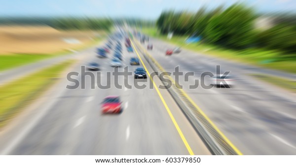 Highway road\
with blur effect. Blurred in motion an asphalt roadway and moving\
cars. Afternoon traffic on a road with multiple lanes. Commuter\
transport. Trip. Blur\
background.