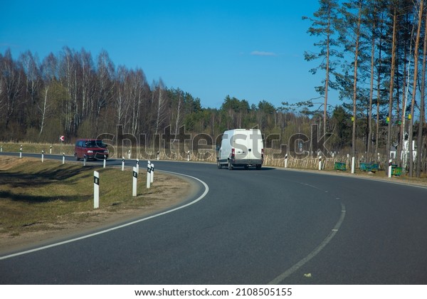 highway road in the\
countryside, roadside and gray asphalt, green forest and blue sky\
on a sunny day	