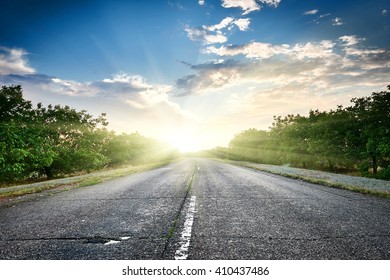 Highway Road At Sunset, Travel And Transportation Concept, Cloudy Sky And Sun On Horizon, Beautiful Summer Landscape