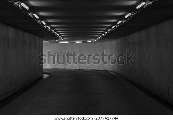 Highway road tunnel with\
light coming from the exit, Urban underground tunnel monochrome\
under pass.