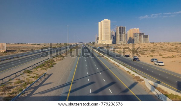 Highway roads in desert with traffic in a big city\
from Ajman to Dubai before sunset from bridge. Transportation\
concept. View from top\
4K