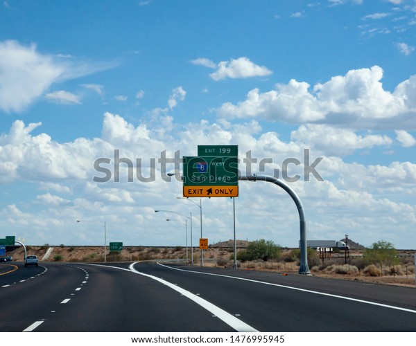 Highway sign for exit to Interstate 8 to San Diego from\
I-10 near Casa Grande, Arizona with trucks in traffic in the\
background.  