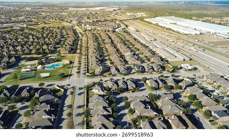Highway stack interchange, pedestrian bridge, open plain from Castle Hills in Lewisville, TX with upscale two-story homes, median street, immature landscaping, HOA pool, tennis court, warehouse. USA