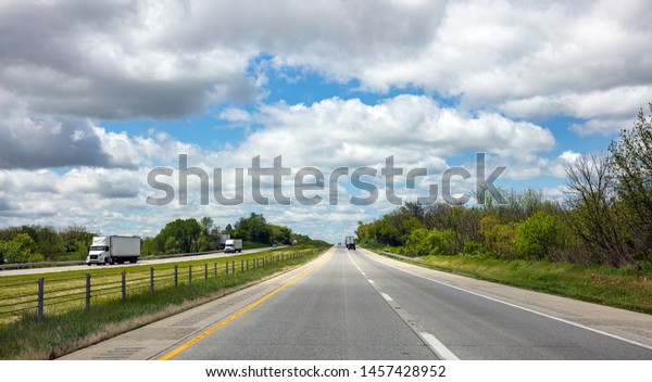 Highway in a\
sunny spring day, USA. National road, passing through American\
countryside. Blue cloudy sky\
background