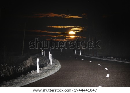 Highway at sunset. Dramatic twilight sky, midnight sun, starlight, moonlight. Dark atmospheric landscape. Panoramic view, copy space, art. Dangerous driving, loneliness, peace, freedom concepts