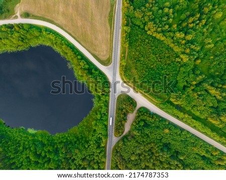 Highway through forest with pine trees and lakes, aerial view. Road with forrest trees and car. Forest road for transpotrs. Aerial above view of freeway. Asphalt road near lake, top view. 
