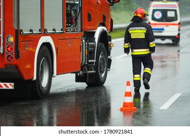 Highway Traffic Accident Site Firefighter Securing Traffic. Firetruck And Ambulance. 