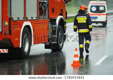 Highway Traffic Accident Site Firefighter Securing Traffic. Firetruck and Ambulance. 