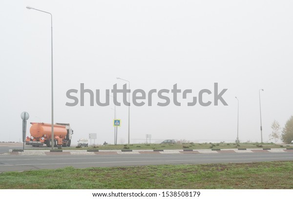 The highway traffic in heavy fog. Cars moving\
on the highway in poor\
visibility