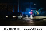 Highway Traffic Patrol Car In Pursuit of Criminal Vehicle, Traffic Stop, Pull Over, Arrest. Police Officer Gets out of Squad Car, Approaches Suspect. Cinematic Action in Industrial Urban Area at Night