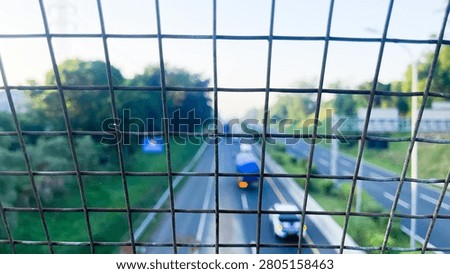 Highway Traffic Viewed Through Wire Mesh Fence with Selective Focus and Urban Transportation Concept