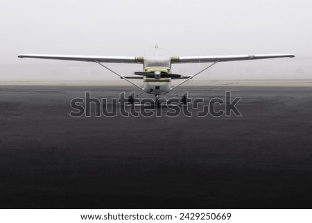 High-Wing Propeller Aircraft parked in morning fog - front view
