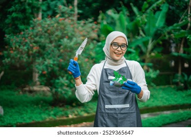 hijab asian woman holding recycled plastic bottel and garden trowel - Powered by Shutterstock