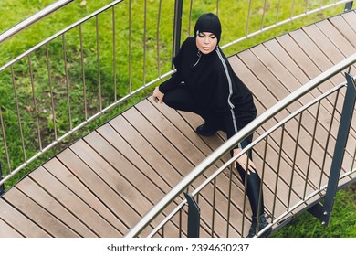 Hijab girl exercising on walkway bridge in early morning. Muslim woman wearing sports clothes doing stretching workout outdoors - Powered by Shutterstock