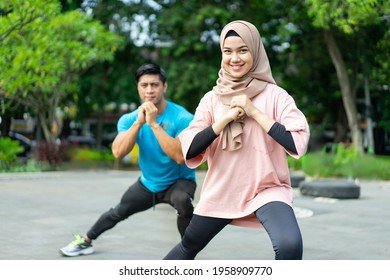 hijab girls doing leg warm-up exercises together before exercising in the park