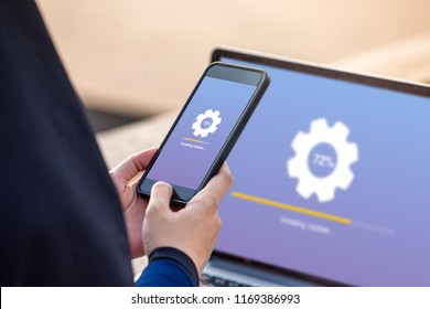 Hijab woman holding smartphone doing installing update process with gearbox percentage progress and loading bar with installing update on screen laptop background