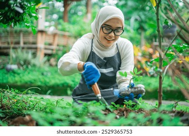 hijab woman troweling soil to plant green vegetable in the garden - Powered by Shutterstock