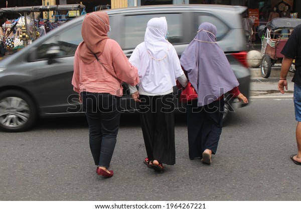 hijab women cross the\
street hand in hand