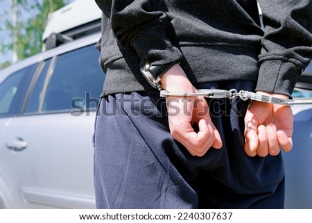 The hijacker in handcuffs at the scene of the crime was detained by the police. Crime, car theft.