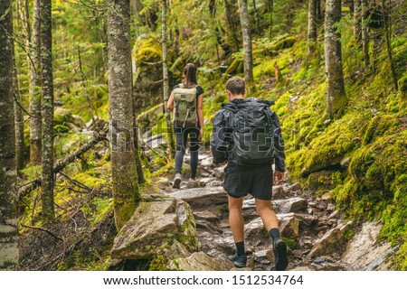 Hike couple hikers hiking forest trail in Autumn nature going camping with backpacks. Friends woman and man walking uphill on mountain in Quebec travel, Canada.