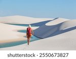 Hiker among  lagoons in the desert of Lencois Maranhenses National Park, Brazil. Unusual natural landscapes.