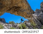 A hiker with arms open under Lexington arch in Great Basin national park. 