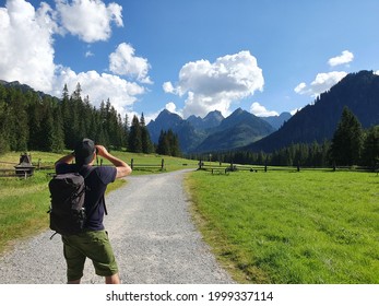 Hiker with backpack holding binoculars and looking at the rocky mountains, Slovakia, Bielovodska valley, High Tatras