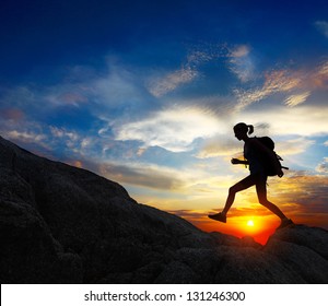 Hiker with backpack jumping over rocks with sunset sky on the background - Powered by Shutterstock