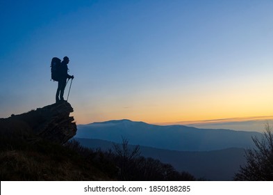 Hiker With Backpack On The Mountain Top Enjoy The Sunset. Symbol Of Lifetime Achievement.