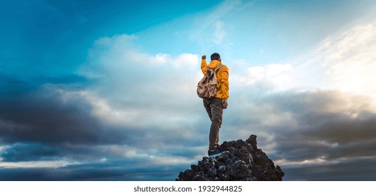 Hiker With Backpack Raising Arms Up On The Top Of The Mountain - Successful Man Celebrating Victory 