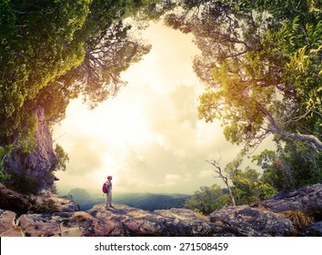 Hiker with backpack standing on the rock surrounded by lush tropical forest - Powered by Shutterstock