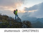 Hiker with backpack standing on top mountain sunset background. Hiker men