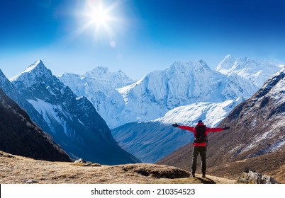 Hiker With Backpack Standing On Top Of A Mountain And Enjoying Sun