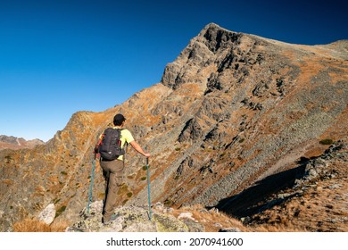 Hiker with backpack and trekking poles looking on peak Krivan Krivan in High Tatras mountains, Slovakia.