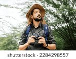 Hiker with backpack using binoculars in the wild. Field biologist or naturalist using binoculars to study wildlife or nature.