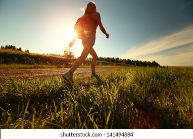 Hiker with backpack walking on a gravel road