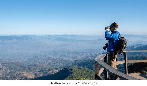 Hiker with backpacks and cameras are using binoculars to take in the views from the high peaks. Travel North of  THAILAND - Powered by Shutterstock