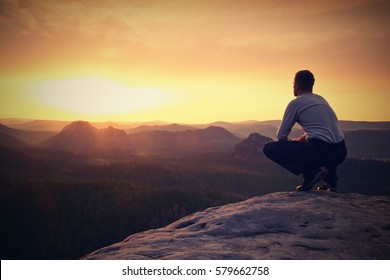 Hiker in black sit alone on the rock summit. Wonderful daybreak in mountains, heavy mist in deep valley. Man sit on the rock. - Powered by Shutterstock