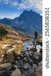 A hiker casually strolls across a stream while hiking through the cascade mountain range in Washington State. 