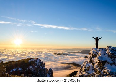 hiker celebrating success on top of a mountain in a majestic sunrise - Shutterstock ID 240905716