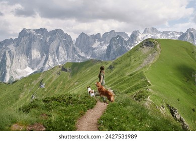 Hiker and dogs on a verdant mountain trail. A woman accompanied by two pets enjoys a hike on a lush path with nature - Powered by Shutterstock