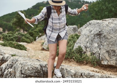 A hiker dressed in casual outdoor attire uses a map and compass to navigate through rocky terrain in a wilderness area, embodying the spirit of adventure and exploration. - Powered by Shutterstock