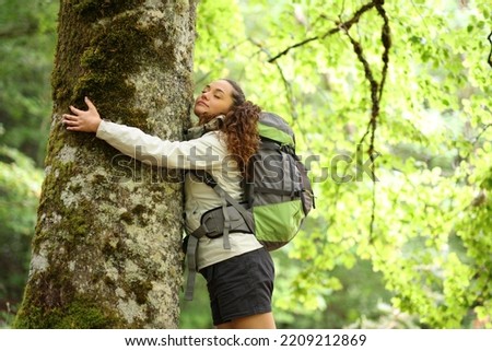 Hiker embracing a big tree in a forest