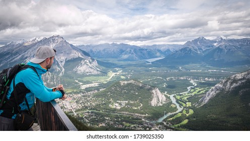 Hiker enjoying view on beautiful alpine valley with mountains and river flowing through it, shot at Sulphur Mountain Lookout, Banff National Park, Alberta, Canada