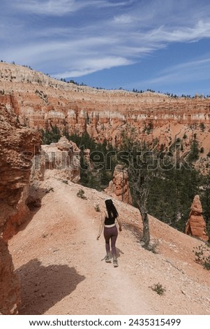 A hiker explores the rugged trails of Bryce Canyon, marveling at the distinctive red hoodoos and vast geological wonders.