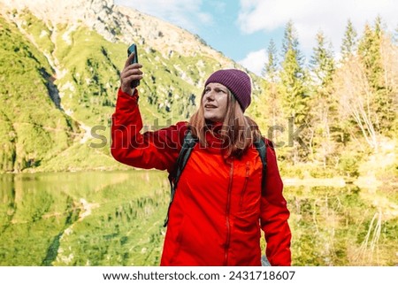Hiker female has lost the cellular signal and lift up the smartphone to improve the quality of communication. Signal strength internet and roaming concept. 