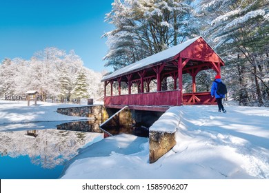A hiker getting ready to cross a covered bridge in the winter